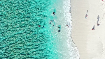 人们在蓝色清澈的海岸边度假玩水实拍视频
