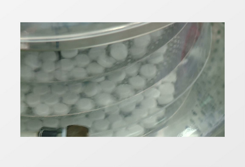 在机器内旋转的托盘上放着圆形的白色药丸实拍视频素材