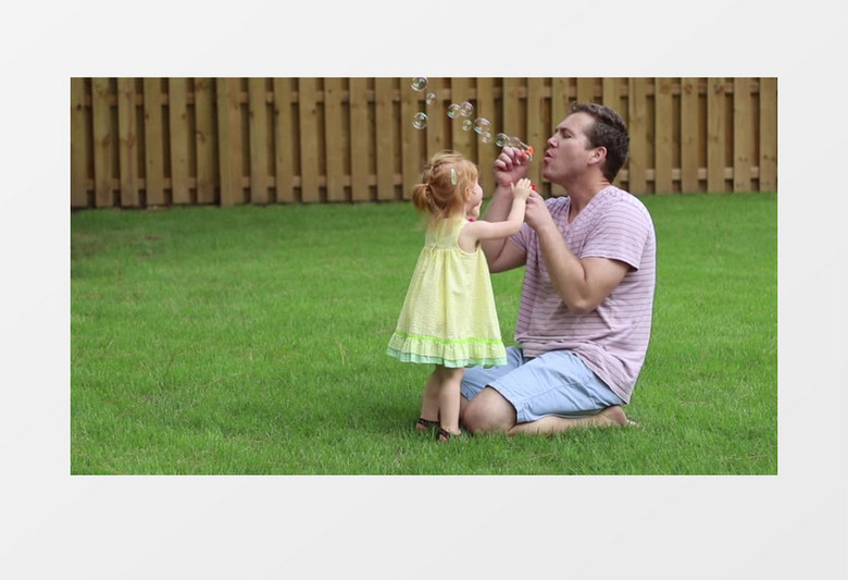 爸爸陪着女孩在草地上吹泡泡实拍视频素材
