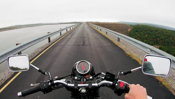 骑行摩托车行驶在湖边道路上实拍视频素材