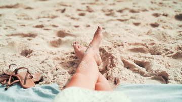 涂着指甲油的女人躺在沙滩上实拍视频素材
