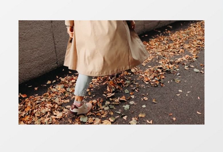 女人阔步走在地面的落叶上实拍视频素材