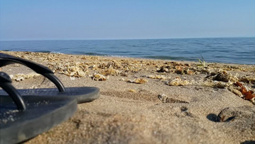 近距离拍摄土耳其海边海滩岸边黑色拖鞋实拍视频素材