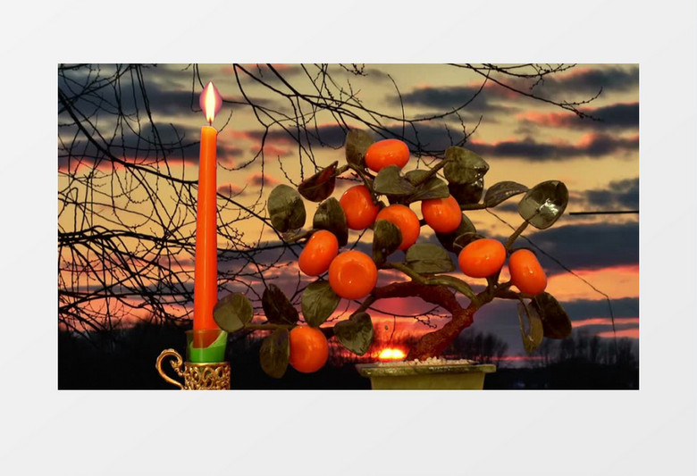 黄昏背景橘子盆栽旁烛台上燃烧的蜡烛烛光跳动视频素材