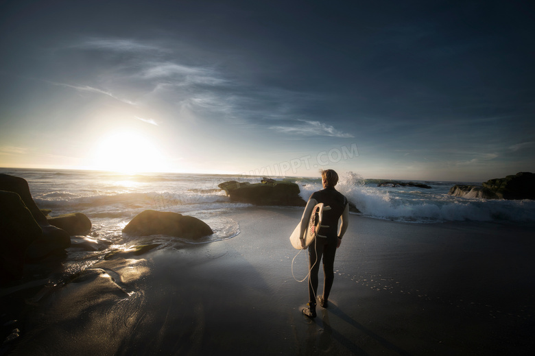 站在沙滩上准备冲浪的男子摄影图片