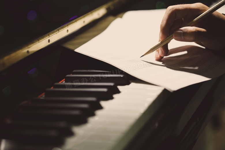 钢琴琴键上写谱子的手特写高清图片