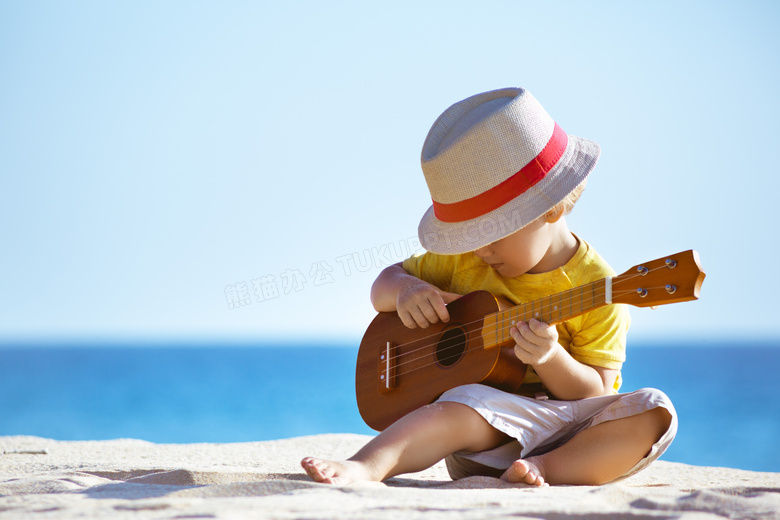 在海边沙滩上弹吉他的小孩高清图片