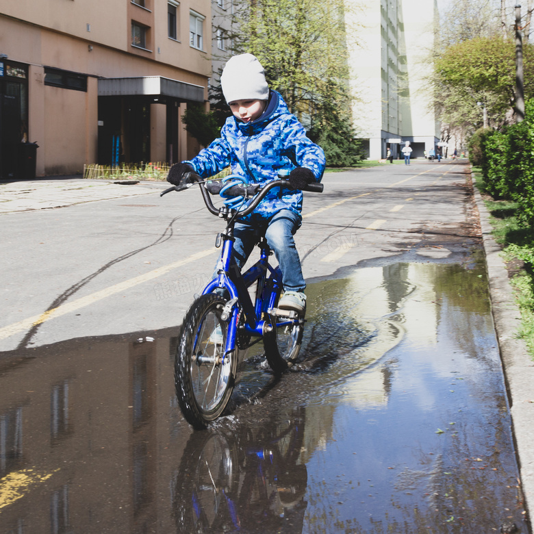骑车通过积水区的小孩摄影高清图片