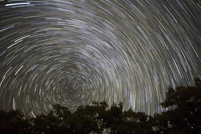 树木剪影与空中的星轨摄影高清图片