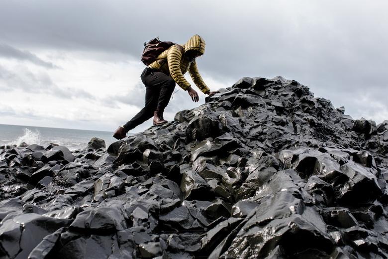 海边爬上礁石的背包客摄影高清图片