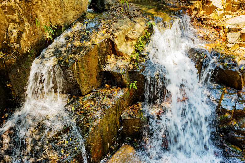 山上岩石流淌着的瀑布摄影高清图片