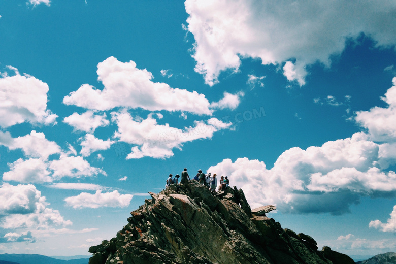 白色云朵与山顶上的登山者高清图片