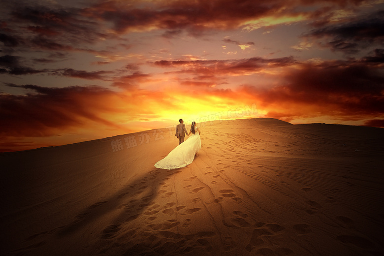 黄昏下沙漠中行走的情侣摄影图片