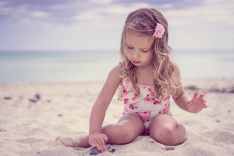 在沙滩上玩着沙子的小女孩高清图片