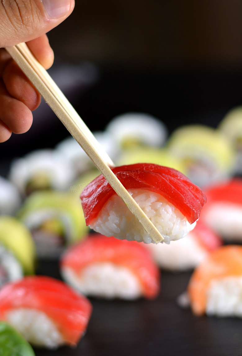 用筷子夹起的美味寿司摄影高清图片