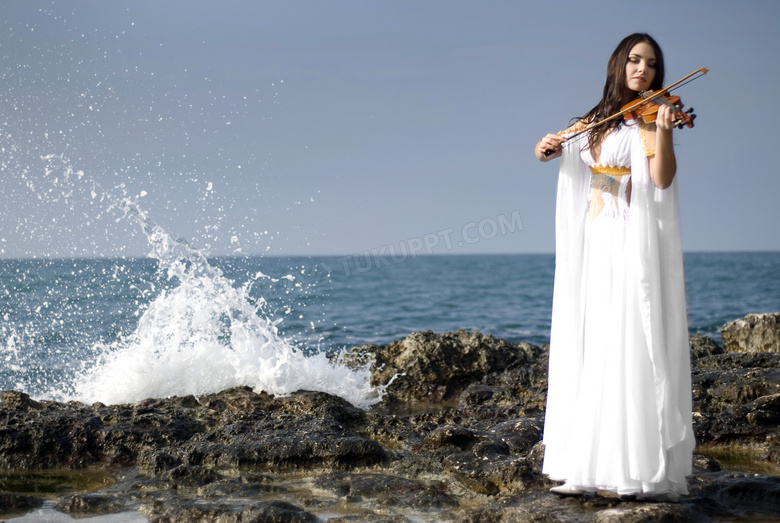 在海边拉小提琴的白裙美女高清图片