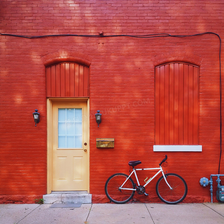 靠着红色墙停放的单车摄影高清图片