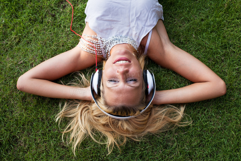 躺草坪上听音乐的美女摄影高清图片