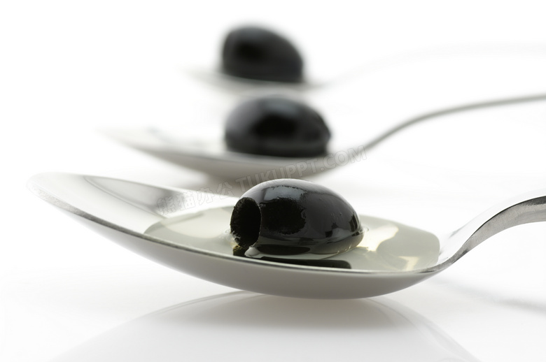 在汤匙里的黑色油橄榄摄影高清图片