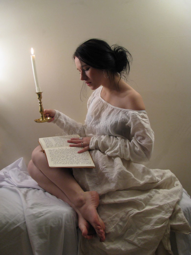 拿着蜡烛在看书的女人摄影图片