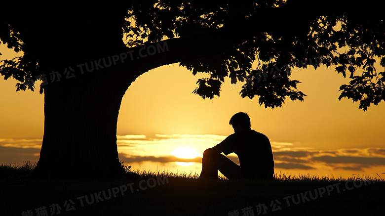 夕阳日出日落坐在草坪上的男人剪影图片