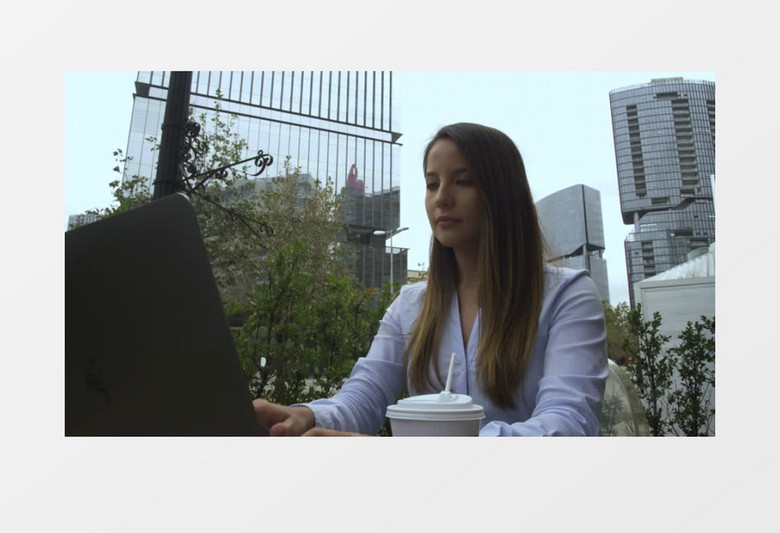 中景拍摄一个女人用笔记本电脑在户外工作实拍视频素材