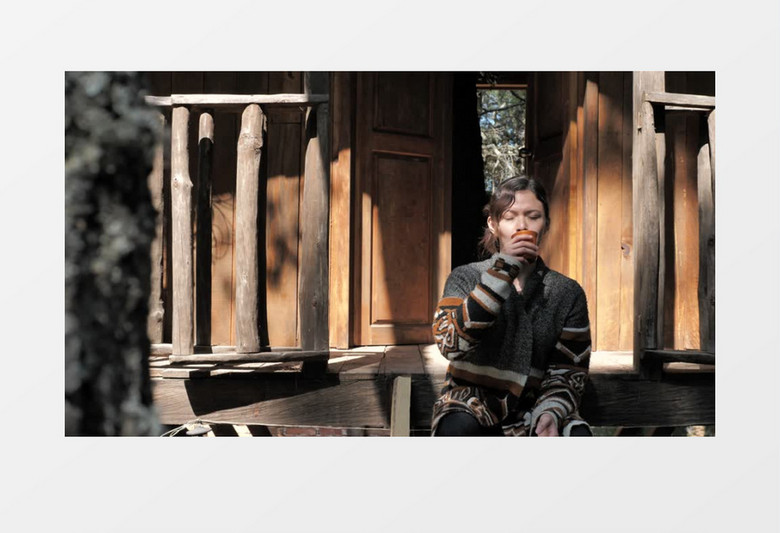 在木屋台阶上用马克杯喝水的女孩实拍视频素材