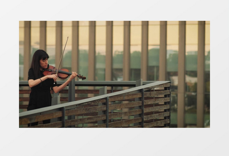 在阳台上拉小提琴的黑发女人实拍视频素材