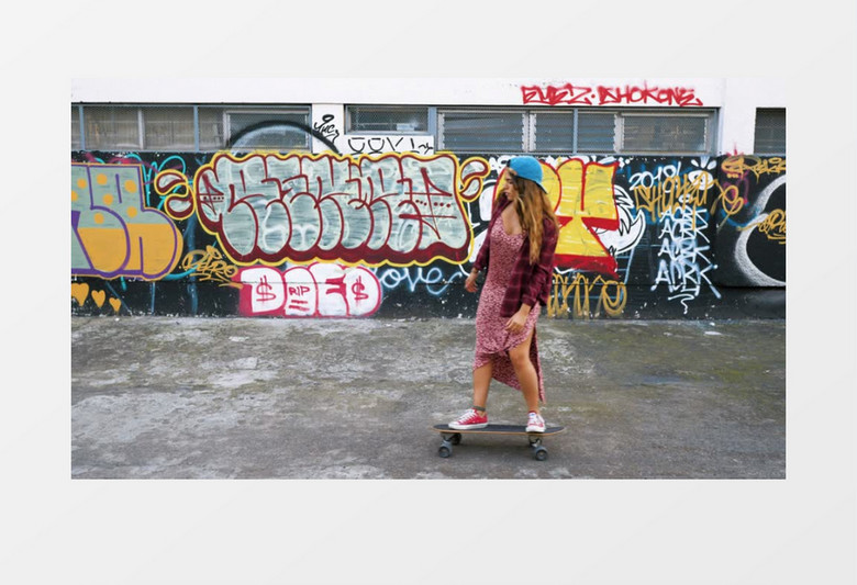 玩滑板的漂亮女孩路过画满涂鸦的墙实拍视频素材