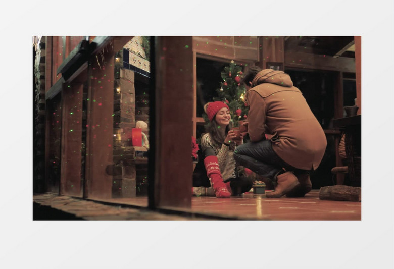 女孩坐在圣诞树边上开心的和朋友分享咖啡实拍视频素材