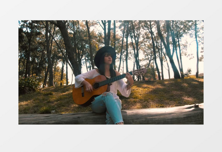坐在枯木上弹吉他的女人实拍视频素材