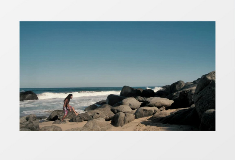 长发男人在海边岩石堆上行走实拍视频