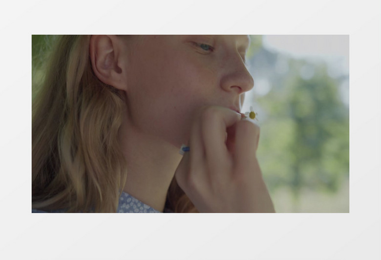 女人拿着一朵小雏菊在公园实拍视频素材