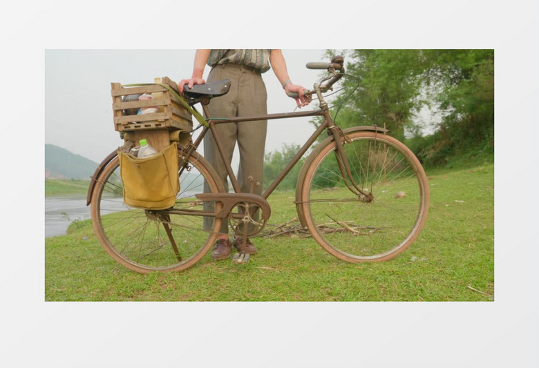 男人在草地上推走了一辆老式自行车实拍视频素材