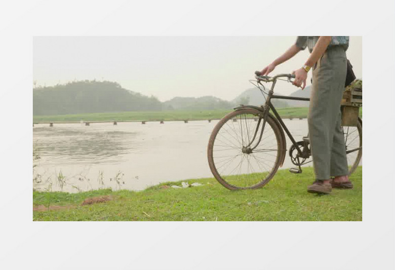 男人在河边推着一辆老式自行车走开实拍视频素材