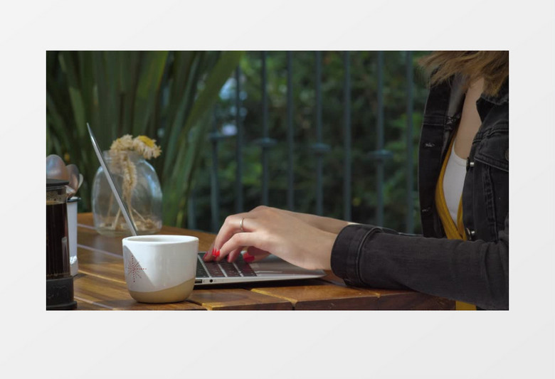 侧面拍摄一个女人在咖啡店里用笔记本电脑打字实拍视频素材