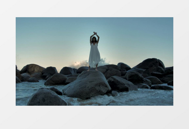 穿着白色连衣裙的女孩在海边礁石上舞动实拍视频素材