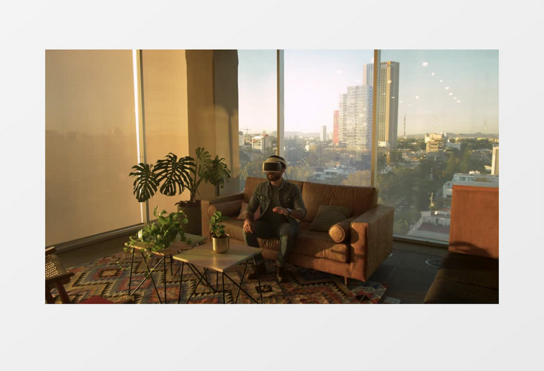 全景拍摄男子坐在沙发上看VR实拍视频素材