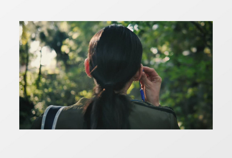 高清拍摄黑色长发的年轻女子在户外戴上耳机实拍视频素材