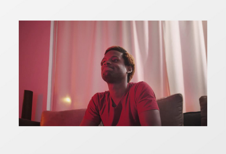 身穿红色衣服的男子正在沙发上打游戏实拍视频素材