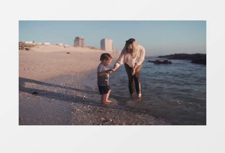 妈妈领着宝宝在海边踢水里走实拍视频素材