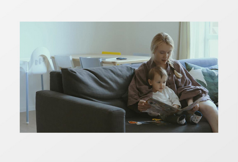 妈妈在沙发上陪着宝宝读画本实拍视频素材