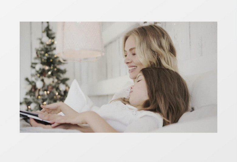 妈妈陪着女孩在床上翻看画册实拍视频素材