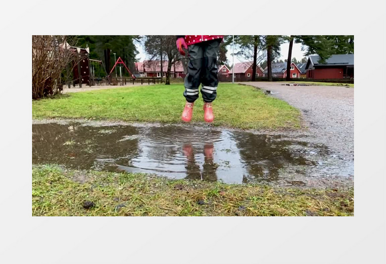 小女孩穿着雨靴在水坑跳跃实拍视频素材