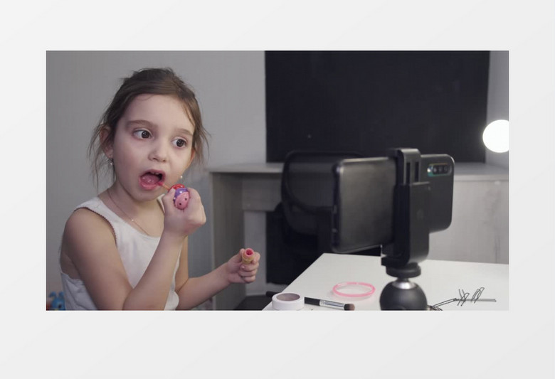 小女孩对着手机在涂彩色唇彩实拍视频素材