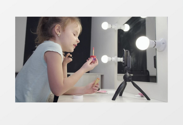 小女孩在对着手机画唇彩实拍视频素材