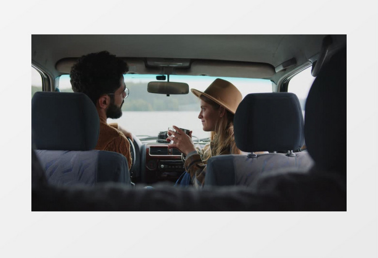 男孩坐在车内跟女孩交谈并指向前方实拍视频素材