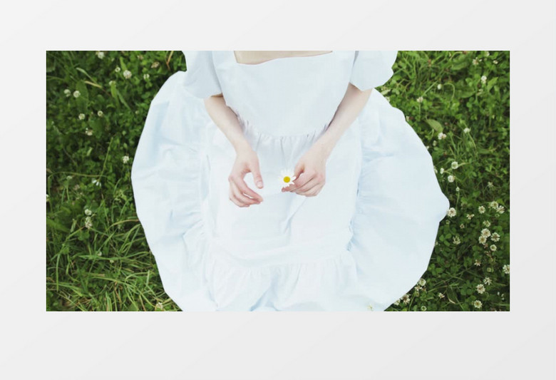 俯拍白裙女人坐在草地上揪花瓣实拍视频素材