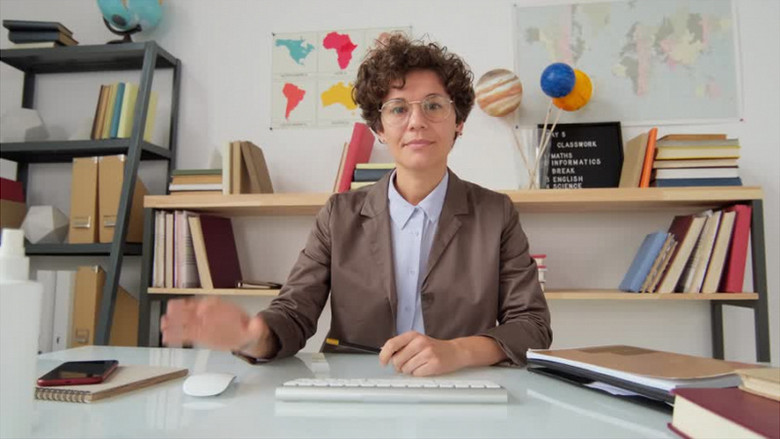 一个戴着眼镜的女老师在书架前给学生上网课实拍视频素材