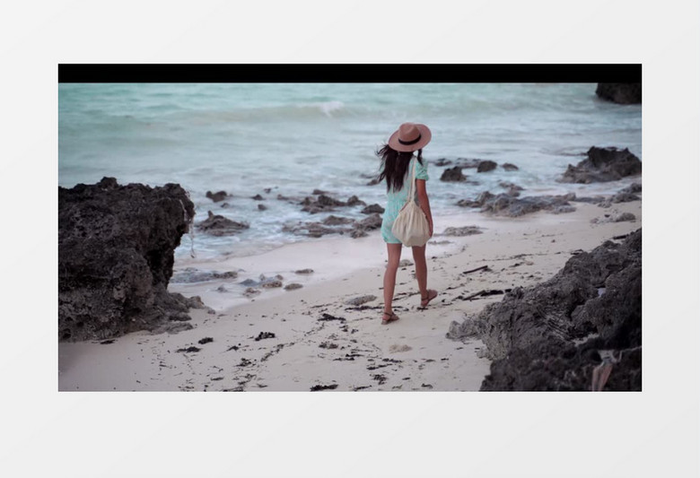 女人背包走在海边的礁石滩实拍视频素材